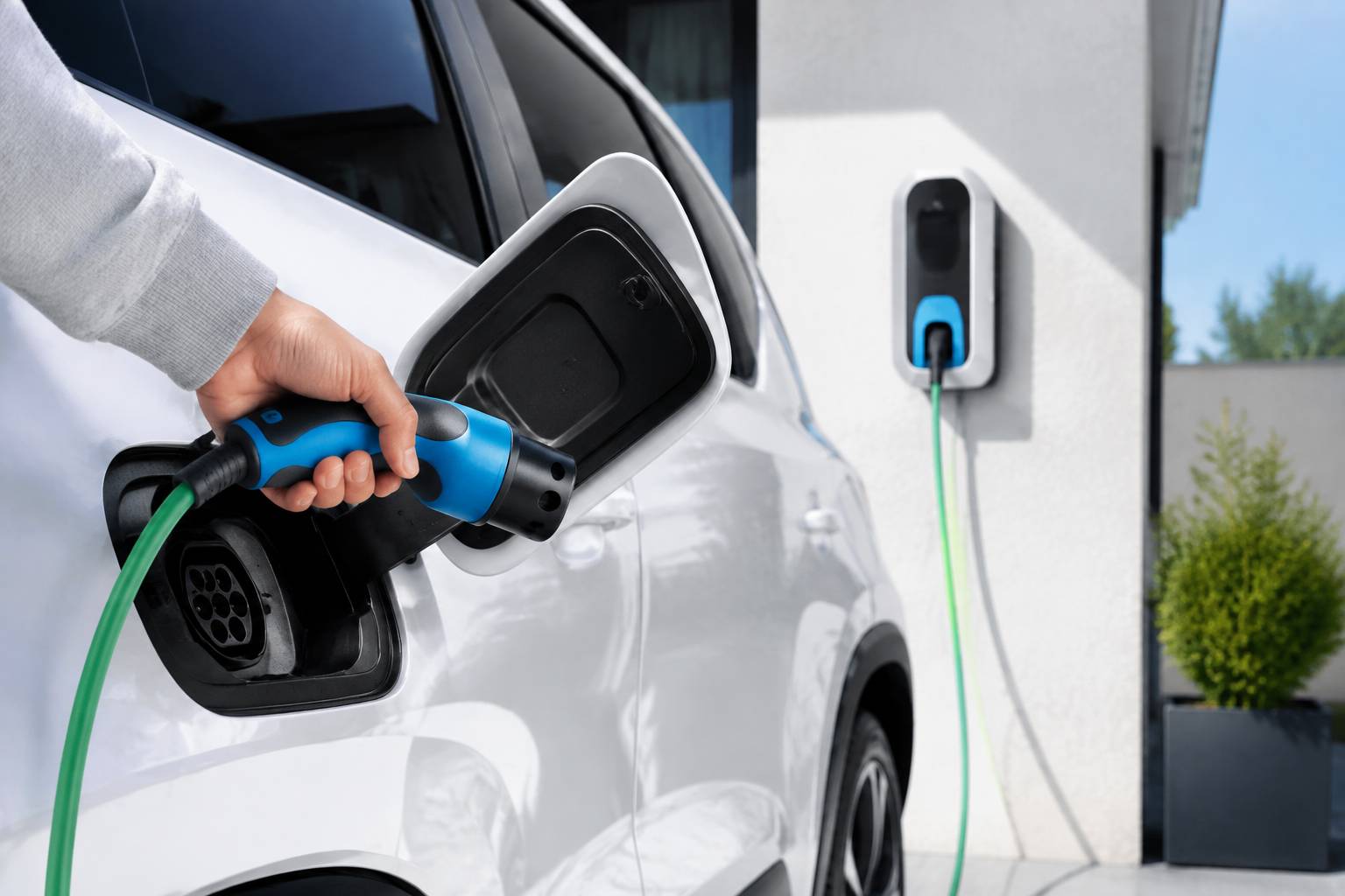 Main débranchant le câble d'une borne de recharge murale